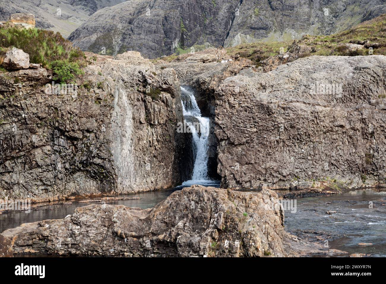 Feen Pools Wasserfall fällt in einen ruhigen Pool, der von zerklüfteten Klippen auf der Isle of Skye umgeben ist und die raue Schönheit des schottischen Highlands einfängt Stockfoto