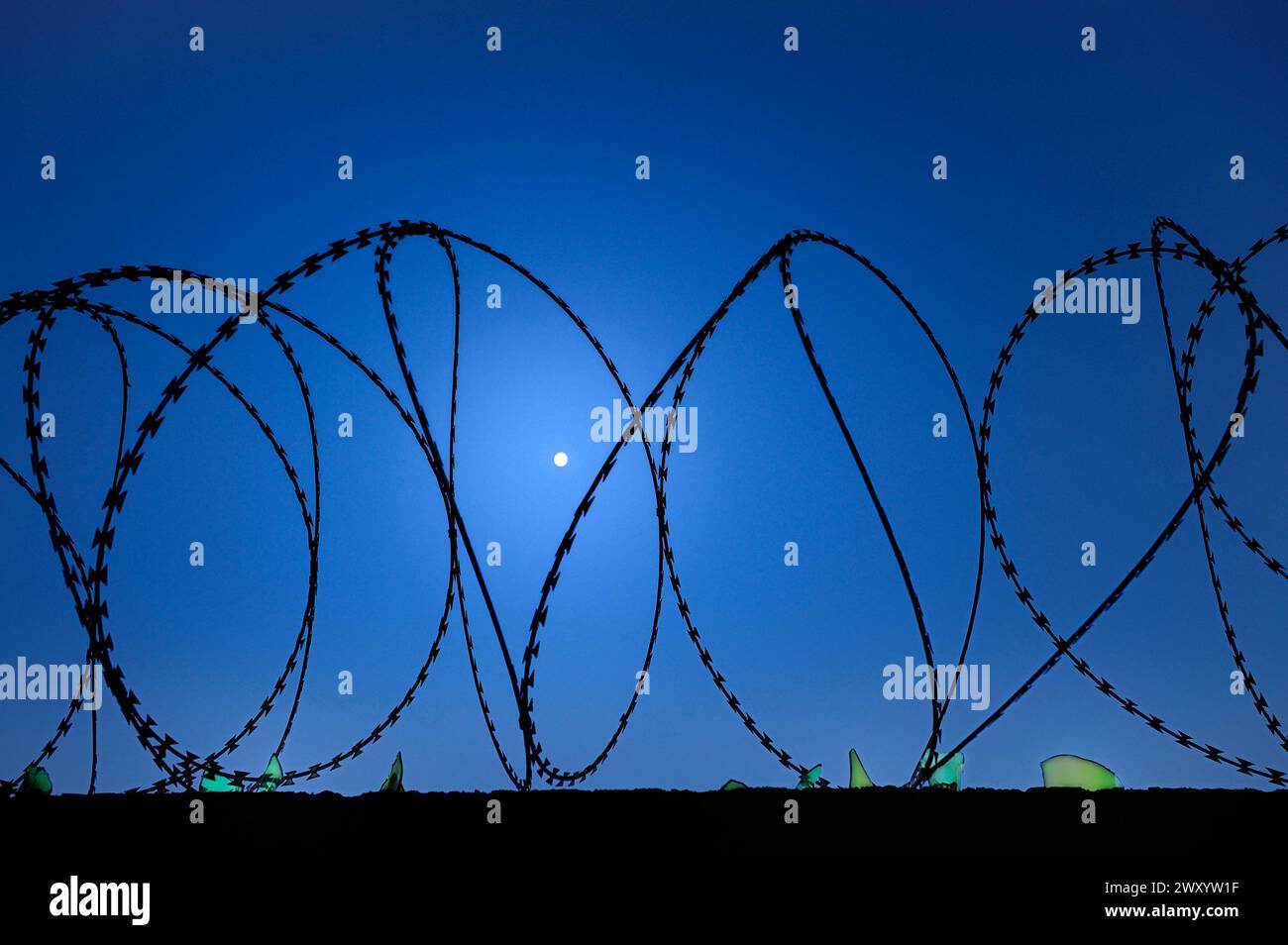 Kourou, Französisch-Guayana: Stacheldraht- und Glasscherben auf dem Gelände der französischen Raumfahrtagentur CNES und Mond am Himmel Stockfoto