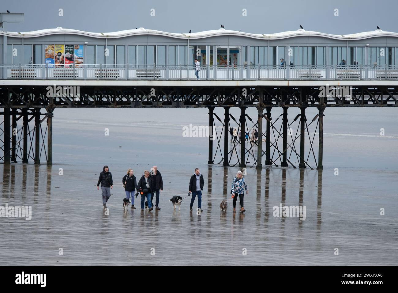Leute laufen an einem kalten, nassen, windigen, regnerischen Strand. Stockfoto