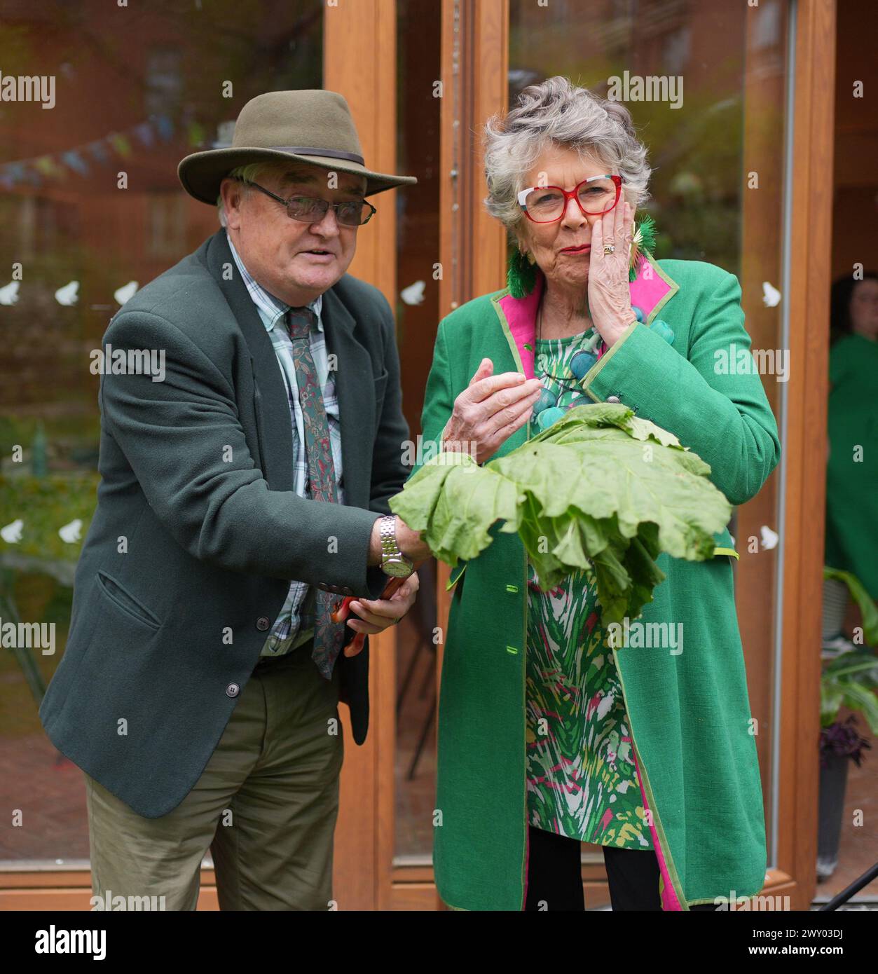 Prue Leith wird während der Auftaktveranstaltung des diesjährigen The Big Lunch at the Phoenix Garden, einem Gemeinschaftsgarten in London, mit Rhabarber von Brian Hickey aus Southend, Essex, präsentiert. Das große Mittagessen vom 1. Bis 2. Juni fördert Gemeindeversammlungen, die Geld für gute Zwecke sammeln und Menschen zusammenbringen. Seit 2015 wurden bei Big Lunch Events 87 Millionen Pfund für gute Zwecke gesammelt. Bilddatum: Mittwoch, 3. April 2024. Stockfoto