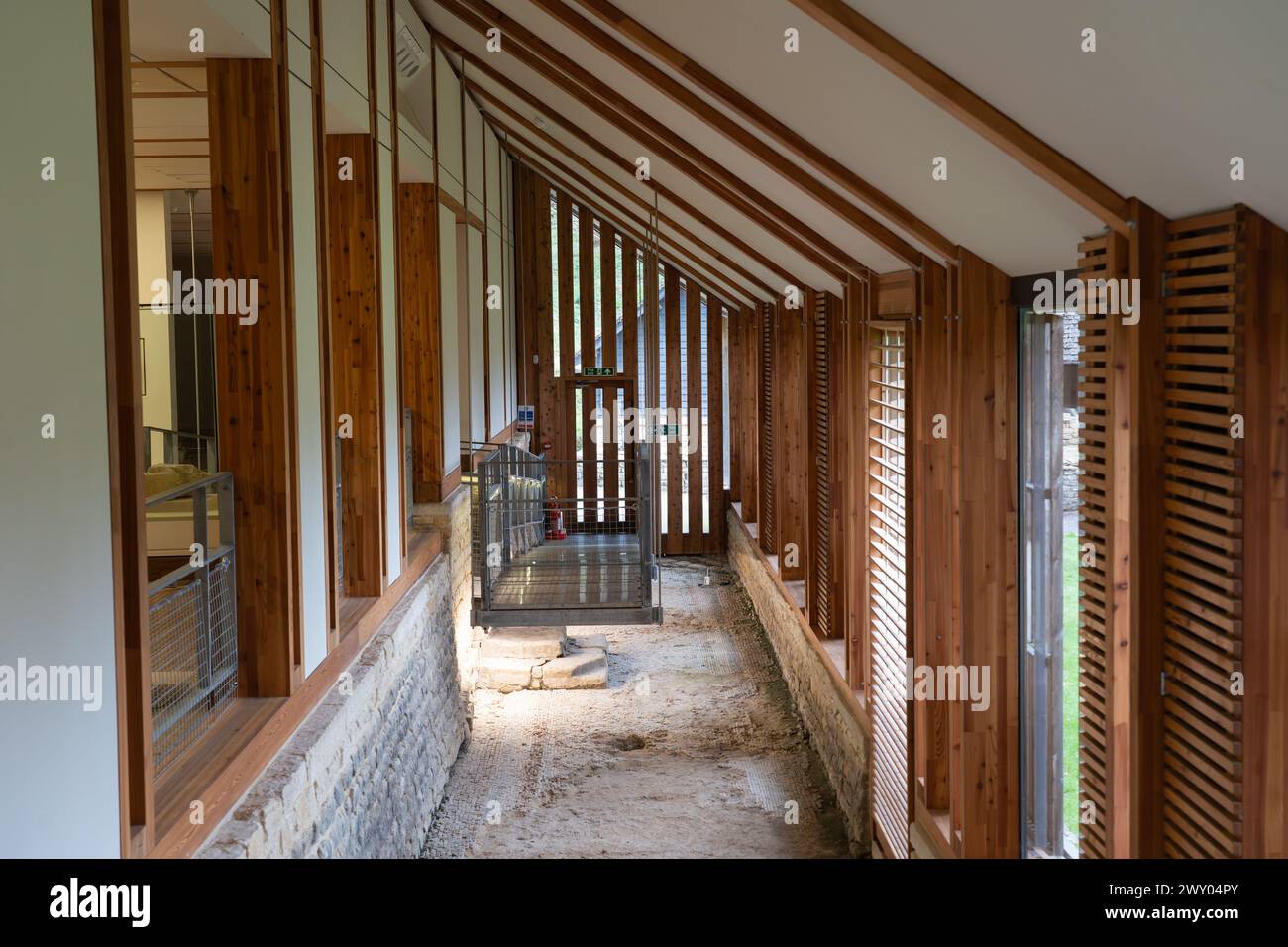 Korridor im Deckgebäude für die Westkette der Chedworth Roman Villa mit offenem Original Mosaikboden darunter, England Stockfoto