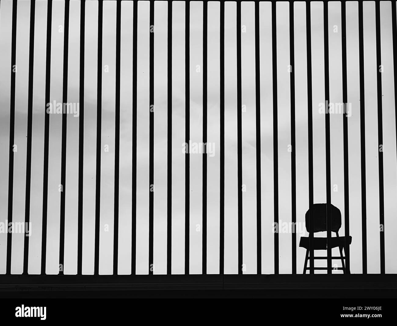 Einsamkeit Eingeschränkt. Der Stuhl Hinter Metallstangen. Minimalismus. Schwarz-weiß. Schwarzweiß. Stockfoto