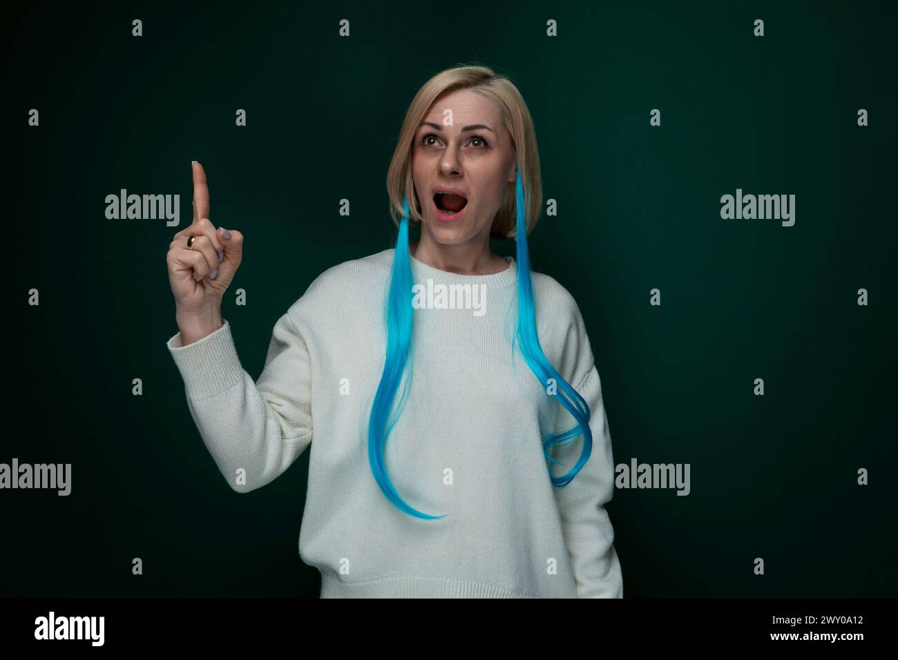 Frau mit langen blauen Haaren, die auf die Kamera zeigt Stockfoto