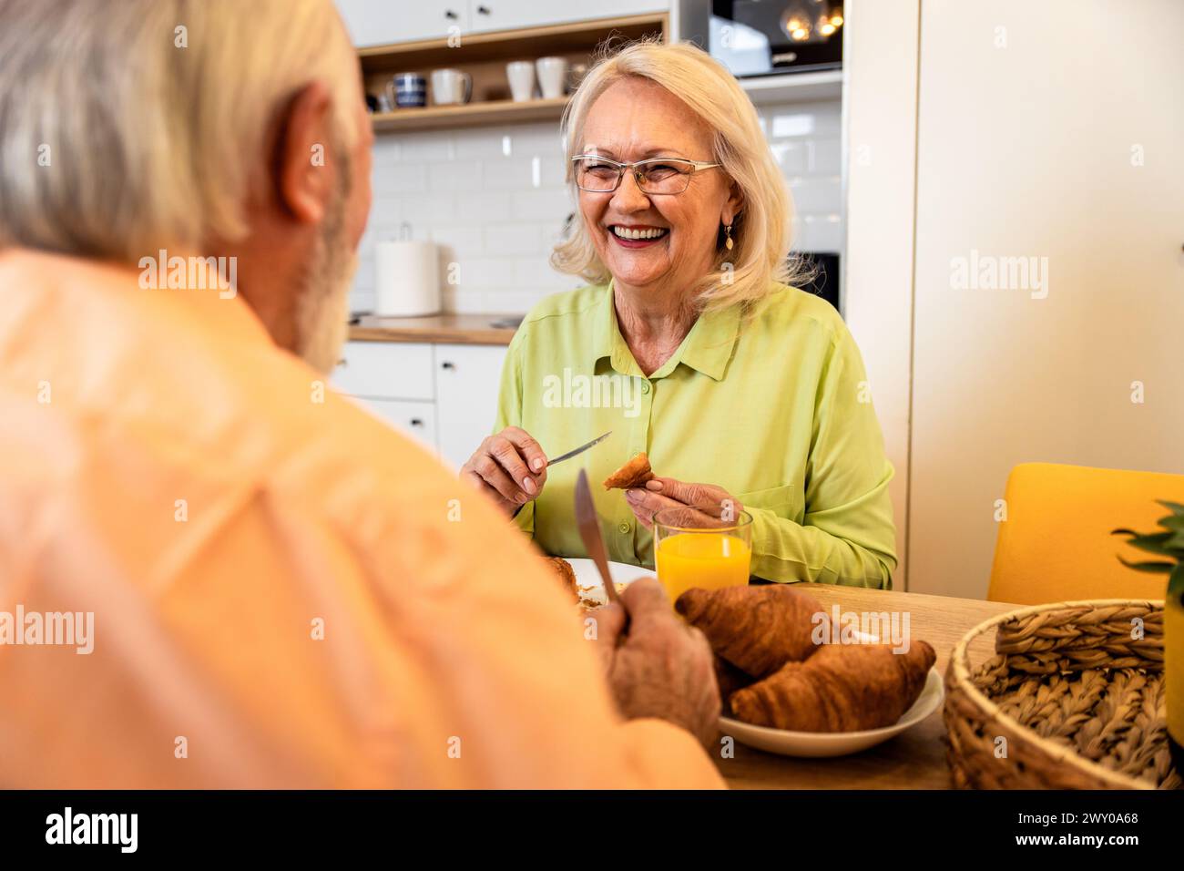 Lächelndes Seniorenpaar, das zu Hause frühstückt. Stockfoto
