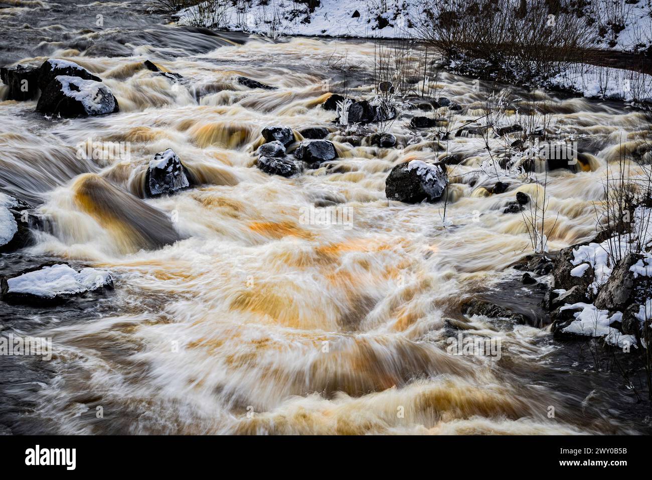 Ein Fluss mit schlammigem Wasser, das über Felsen fließt Stockfoto