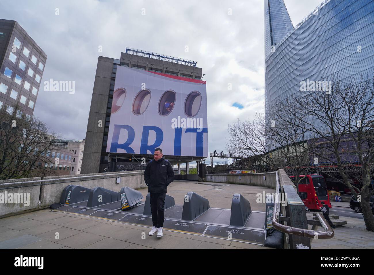 London 3 April 2024 . Ein großes Werbeplakat ziert die Fassade eines Gebäudes in der London Bridge mit einem Passagier, der aus einem Flugzeugfenster über das Wort „BRIT“ blickt, als Teil der neuen British Airways Kampagne Credit: amer ghazzal/Alamy Live News Stockfoto