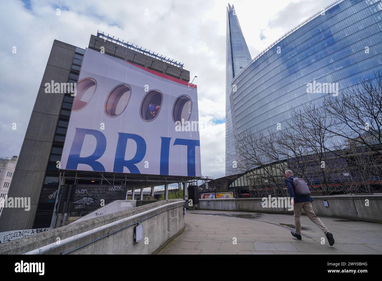London 3 April 2024 . Ein großes Werbeplakat ziert die Fassade eines Gebäudes in der London Bridge mit einem Passagier, der aus einem Flugzeugfenster über das Wort „BRIT“ blickt, als Teil der neuen British Airways Kampagne Credit: amer ghazzal/Alamy Live News Stockfoto