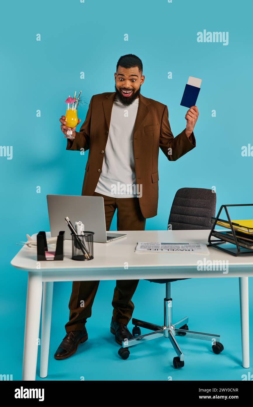 Ein Mann mit einem ernsten Ausdruck, der an einem Schreibtisch sitzt, eine Karte in der einen Hand hält und mit der anderen Hand auf einem Laptop schreibt. Stockfoto