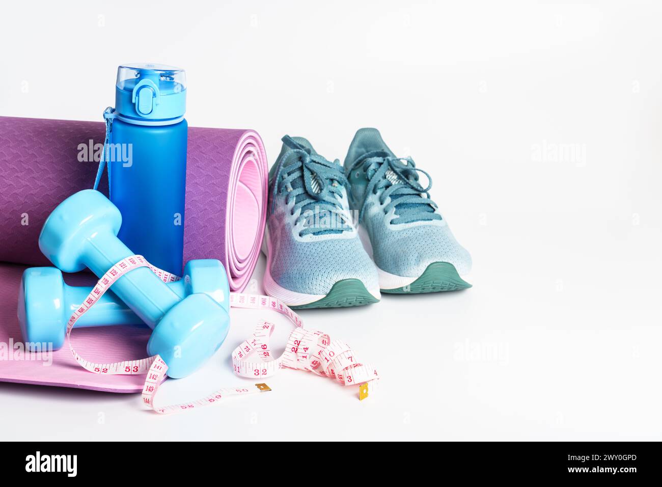 Yogamatte, Turnschuhe, Kurzhanteln und Flasche Wasser isoliert auf weißem Hintergrund. Stockfoto
