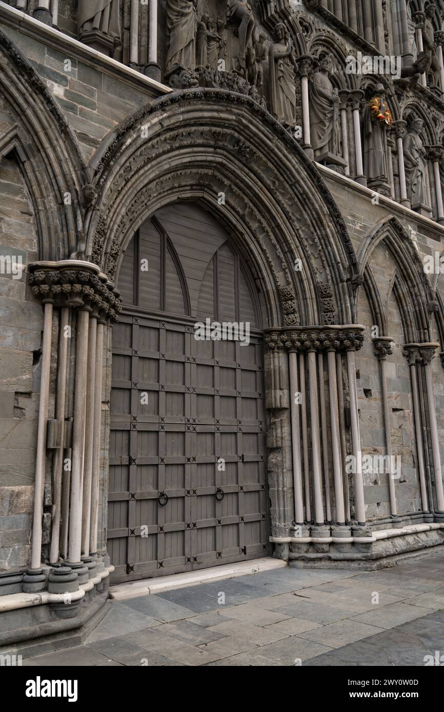 Hölzerne Bogentüren und Steinschnitzereien verzieren den Eingang zum Nidaros Cathedral Arch und spiegeln das reiche architektonische Erbe von Trondheim, Norwegen, wider Stockfoto