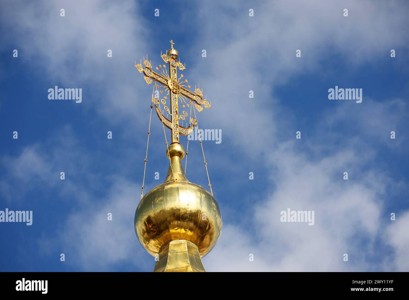 Goldene Kuppel der orthodoxen Kirche mit einem Kreuz gegen den blauen Himmel mit weißen Wolken. Christlicher Tempel Stockfoto