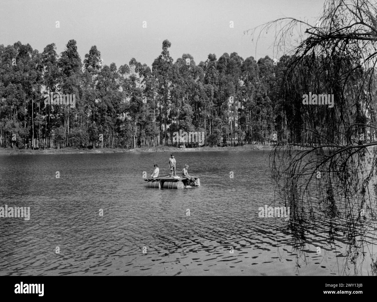 Europäische Jungen auf einem Floß aus Ölfässern, auf einem Fluss, möglicherweise dem Kafubu bei Ndola, Nordrhodesien (heute Sambia) um 1956 Stockfoto