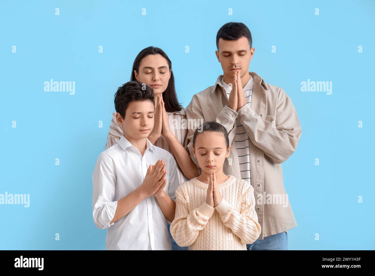 Familie betet zusammen auf blauem Hintergrund Stockfoto