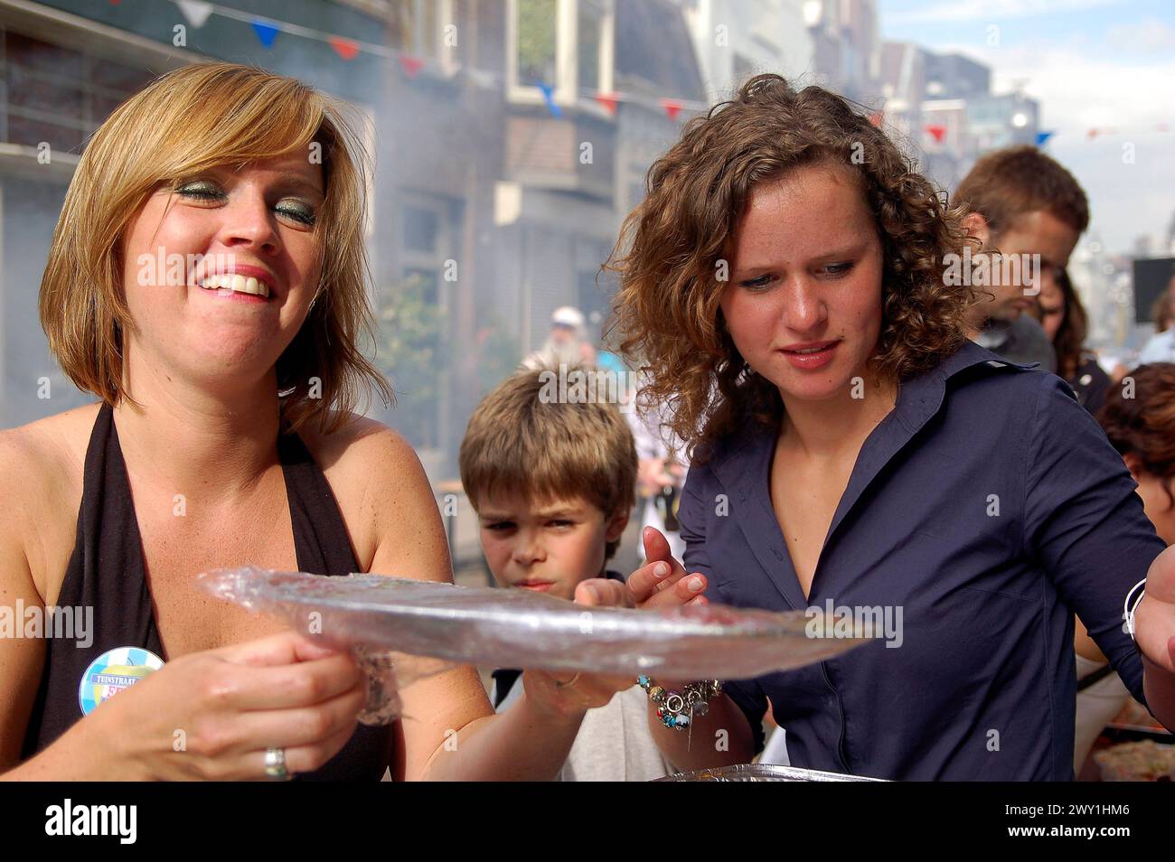 Zwei Frauen servieren Streetfood zwei, junge Erwachsene, kaukasische Frau servieren Streetfood während eines Barbecue/Barbeque in der Nachbarschaft an einem Frühling, Samstagnachmittag im Jahr 2008. Tilburg, Niederlande. Tilburg Tuinstraat Noord-Brabant Nederland Copyright: XGuidoxKoppesx Stockfoto