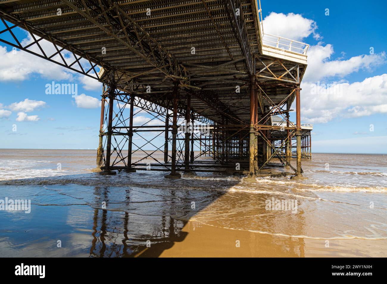 Cromer Pier, Norfolk. Cromer Pier an einem sonnigen Tag mit ein paar weißen Wolken. Ein farbiges Bild der Unterseite des Piers. Die Flut geht aus. Stockfoto