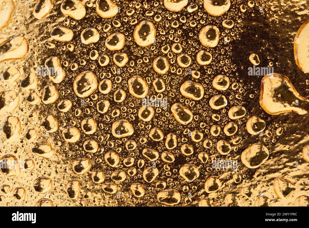 Flüssigkeitstropfen in verschiedenen Größen auf goldenem Hintergrund. Stockfoto