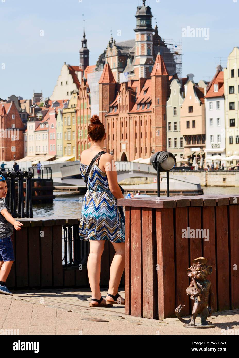 Familientouristen, die an einer kleinen Metallskulptur Hewelion der Löwe in der Altstadt von Danzig, Polen, Europa, EU vorbeifahren Stockfoto
