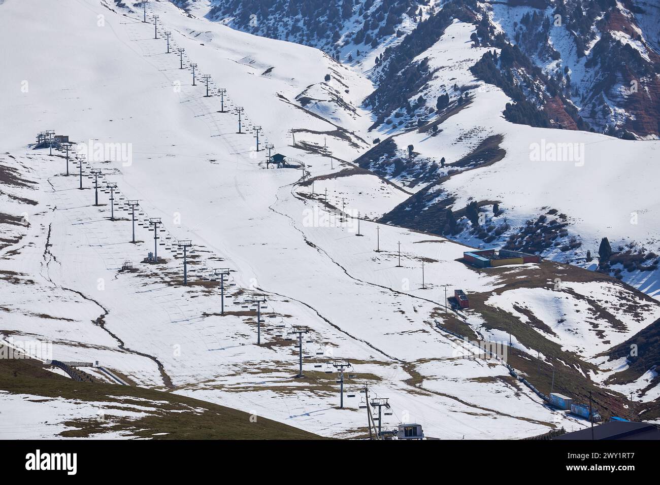 Ende der Saison, leeres Skigebiet. Aufgetaute Flecken auf verschneiten Berghängen. Sessellifte, Blick von oben, aus der Luft. Wintersport, Skifahren, Snowboarder Stockfoto