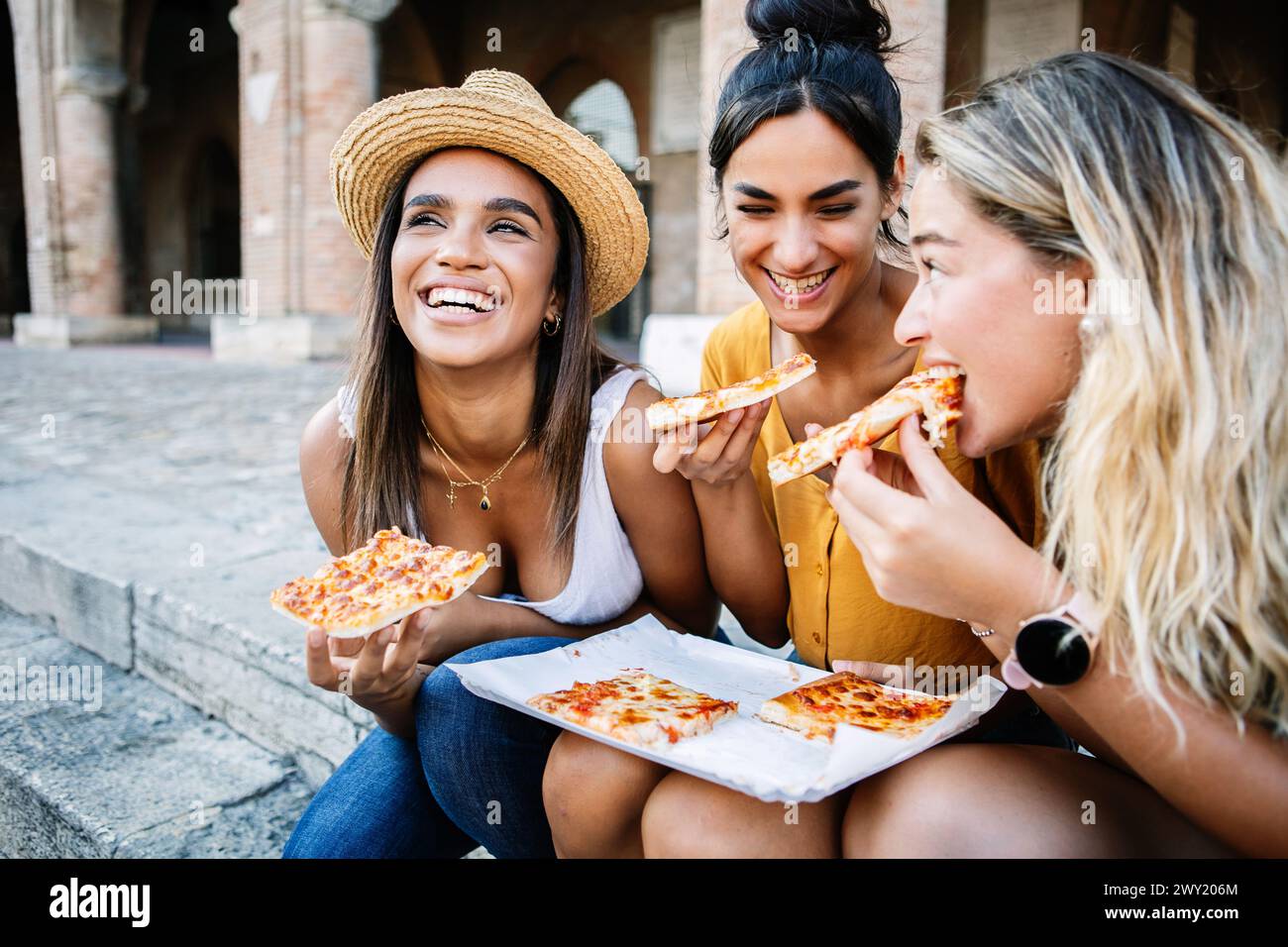 Drei fröhliche Frauen, die Spaß beim Pizza-Essen in Italien haben Stockfoto