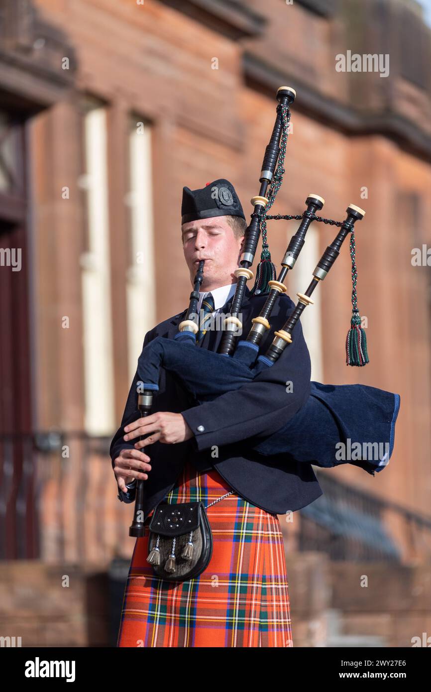 Schottischer Mann im Clantartan, der Dudelsack spielt, ein traditionelles schottisches Musikinstrument. Dumfries, Schottland. Stockfoto