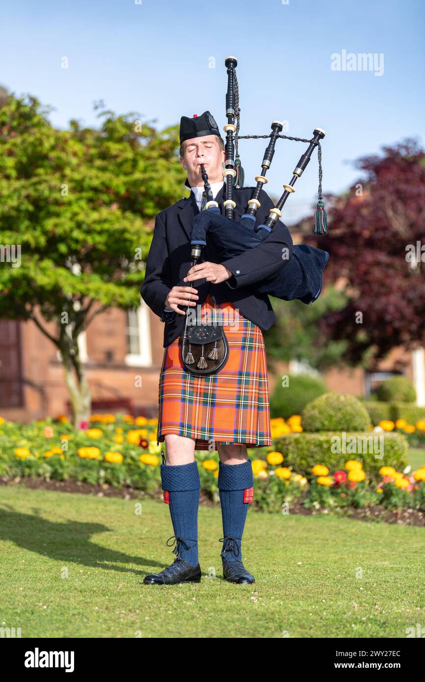 Schottischer Mann im Clantartan, der Dudelsack spielt, ein traditionelles schottisches Musikinstrument. Dumfries, Schottland. Stockfoto