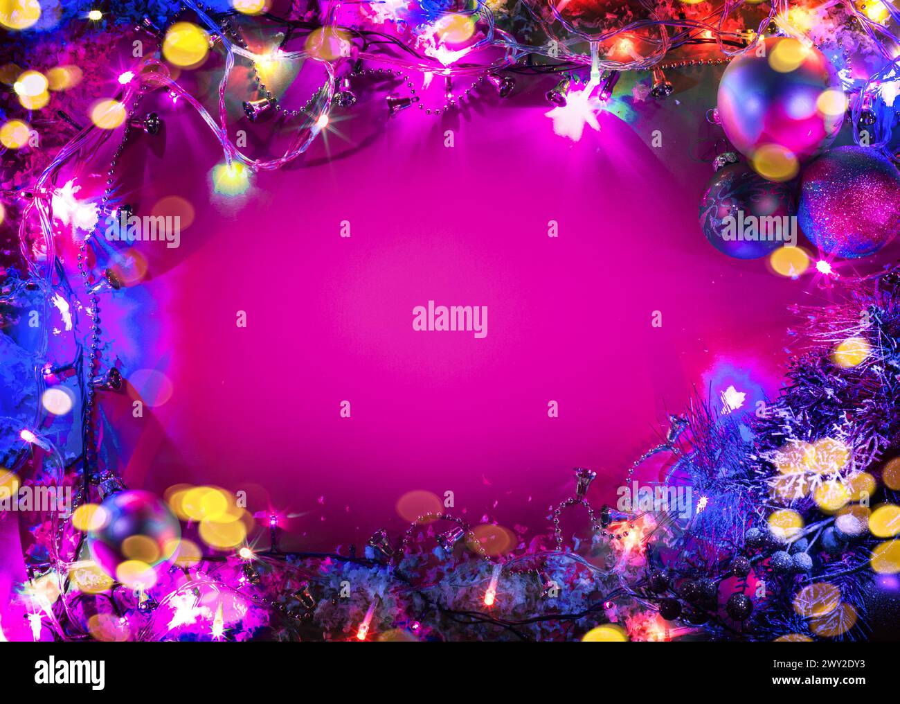 Weihnachtsbaumdekoration mit Feenlichtern, die als Rahmen auf rosafarbenem Hintergrund angeordnet sind. Stockfoto
