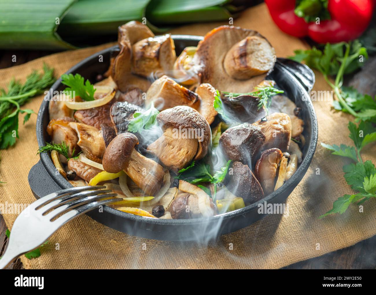 Garen Sie einfach dampfende Steinpilze in der Pfanne auf dem Holztisch. Draufsicht. Stockfoto