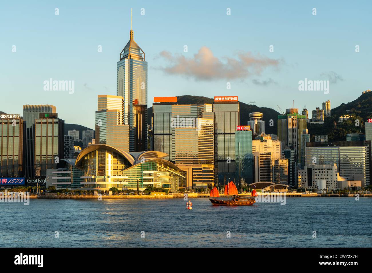 Bei Sonnenuntergang bietet der Hafen von Hong Kong eine atemberaubende Skyline mit Geschäftsgebäuden, die sich auf dem ruhigen Wasser des Victoria Harbour spiegeln. Stockfoto