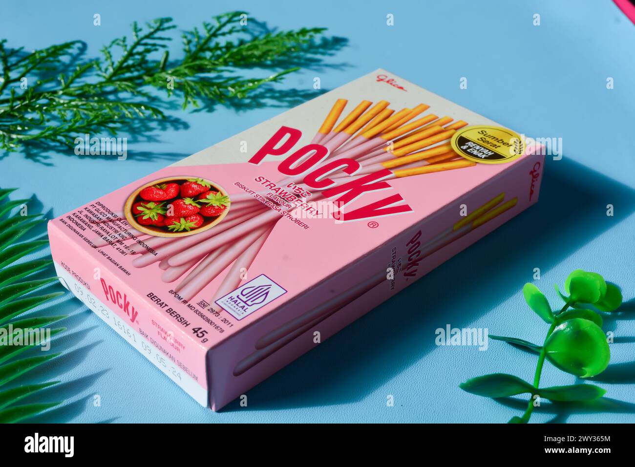 Wonosobo, Indonesien 23. April 2023: Pocky Snacks mit Erdbeergeschmack in rosa Verpackung. Vor blauem Hintergrund. Stockfoto