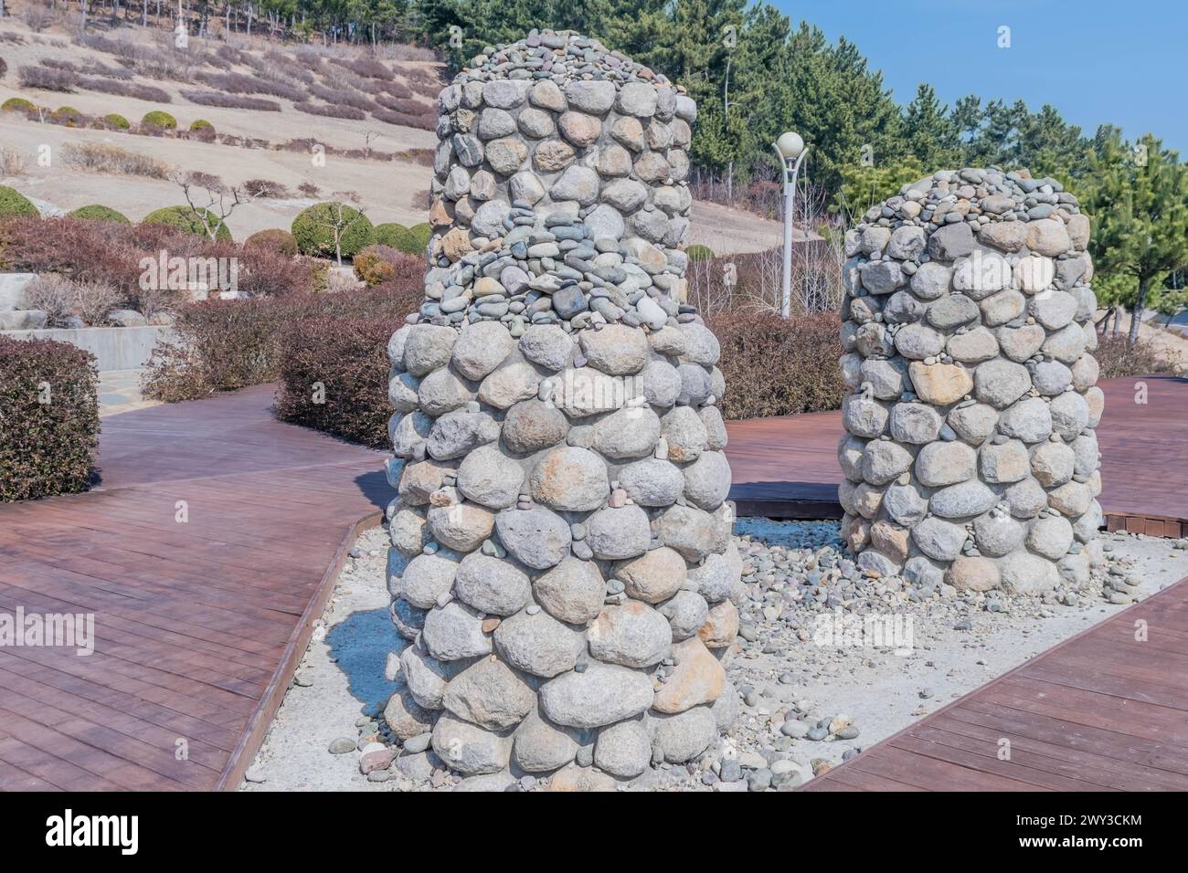 Zwei Steinsäulen stehen auf Kies, umgeben von landschaftlich begrüntem Grün, in Südkorea Stockfoto