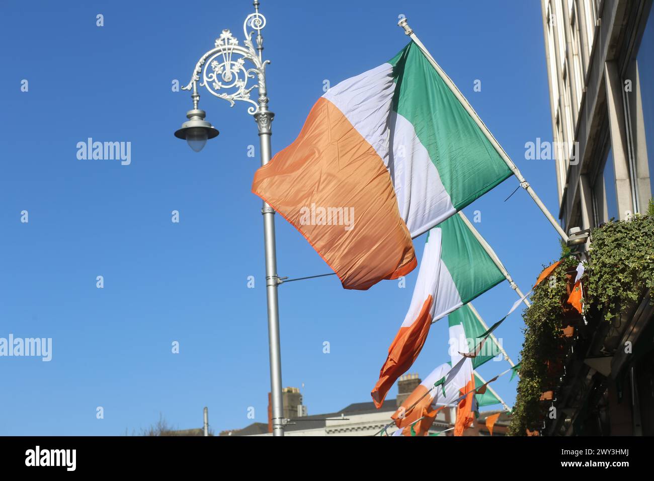 Die irischen Trikolore hängen an einem sonnigen Tag in der Brise. Dublin, Irland Stockfoto