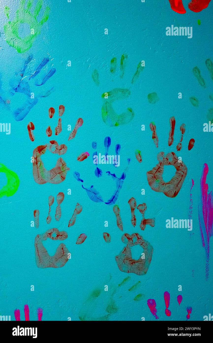 Eine Gruppe farbenfroher Handabdrücke auf einer türkisfarbenen Wand. Stockfoto