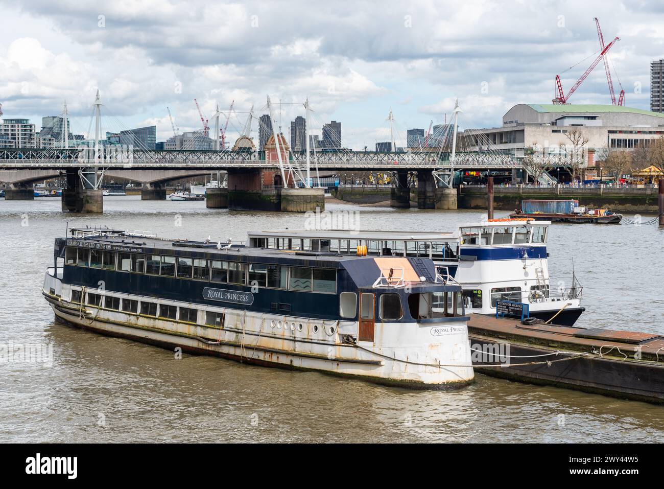 Old Thames Cruises Schiff namens MV Royal Princess legte in Westminster Moorings in London an. Rostiges Vintage-Vergnügungsboot. Hungerford Bridge Stockfoto