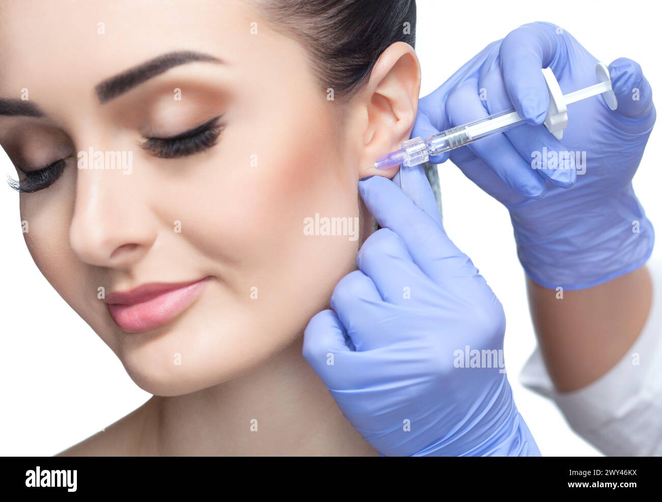 Der Arzt Kosmetikologe führt das verjüngende Gesichtsinjektionsverfahren zur Glättung von Falten und gegen schlaffe Haut am Ohrläppchen von A durch Stockfoto