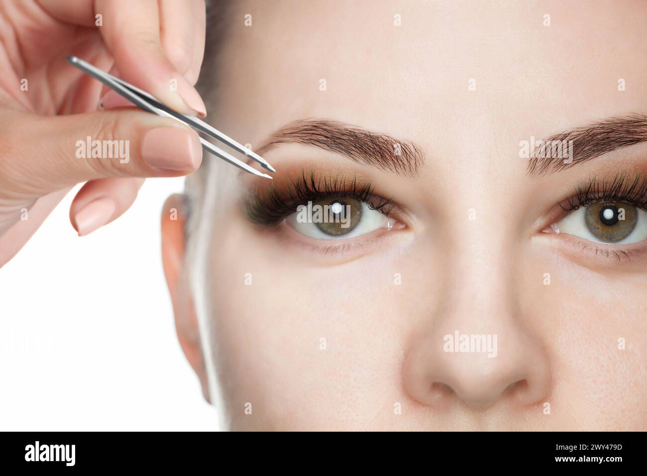 Make-up-Künstler zupft die Augenbrauen einer schönen Frau im Schönheitssalon. Gesicht Nahaufnahme. Professionelle Gesichtspflege. Stockfoto