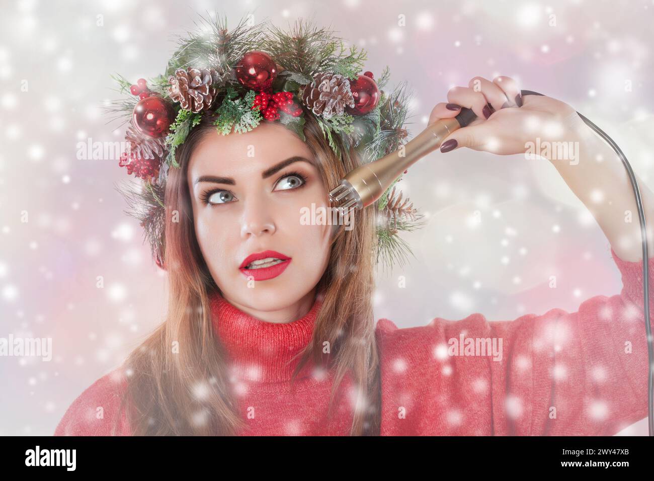 Porträt einer Frau mit einem Tannenkranz mit Kegeln auf dem Kopf, hält in der Hand eine Düse für eine kosmetische Behandlung auf Schneeflocken Hintergrund. HF-Heben Stockfoto