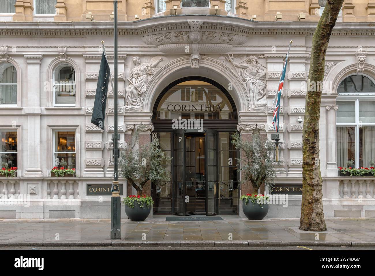 Die bogenförmige Tür des Corinthia Hotels sieht mit Portland-Steinen und skulpturalen Spandrel-Figuren prächtig aus. Stockfoto