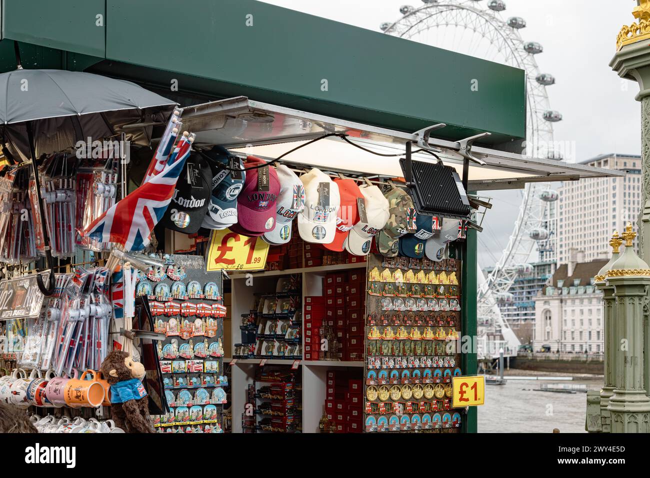 Ein Touristenstand, an dem Souvenirs aus London verkauft werden, mit dem London Eye oder dem Millennium Wheel in der Ferne. Reise und Tourismus, Wirtschaft oder BIP-Konzept. Stockfoto