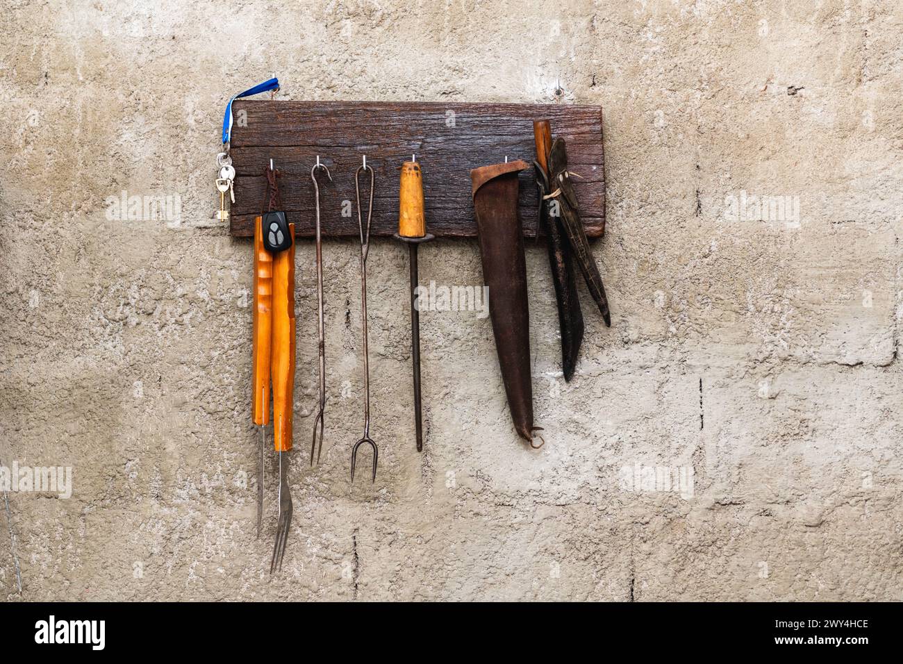 Eine Sammlung von Werkzeugen, die an einer Wand hängen. Zu den Werkzeugen gehören ein Hammer, eine Zange, ein Schraubendreher und ein Schraubenschlüssel. Die Wand besteht aus Beton und h Stockfoto