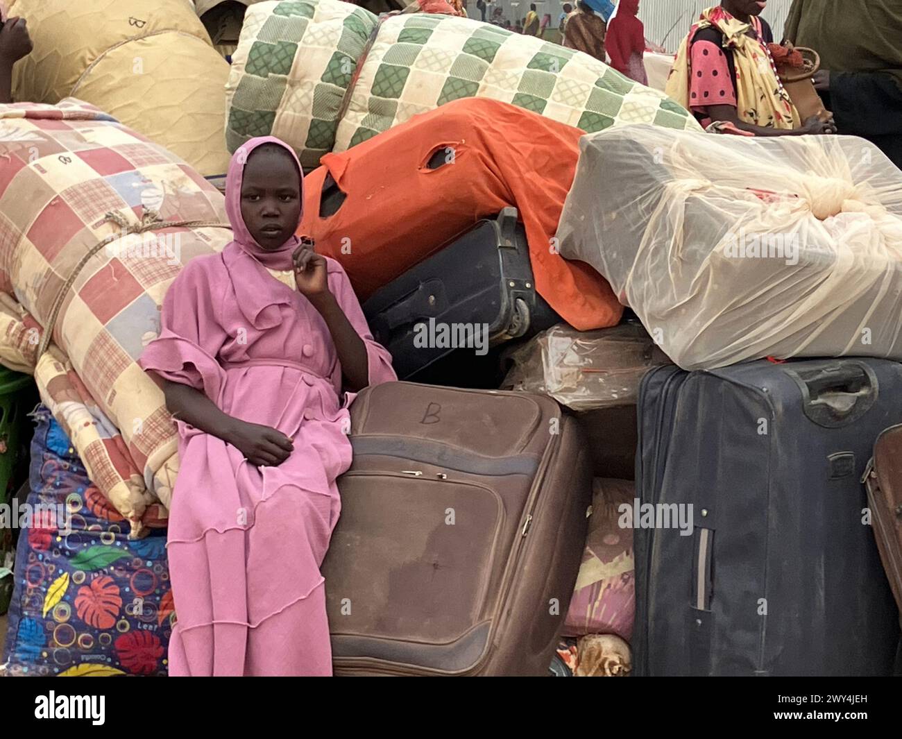 Renk, Südsudan. März 2024. Eine junge Frau aus dem Sudan sitzt in einem Transitlager, umgeben von Koffern und den Habseligkeiten von Flüchtlingen. Der blutige Machtkampf im Sudan, der vor einem Jahr begann, hat jetzt die größte Flüchtlingsbewegung der Welt ausgelöst. Mehr als neun Millionen Menschen fliehen vor den Kämpfen im Sudan und in den Nachbarländern. Eva-Maria Krafczyk/dpa/Alamy Live News Stockfoto