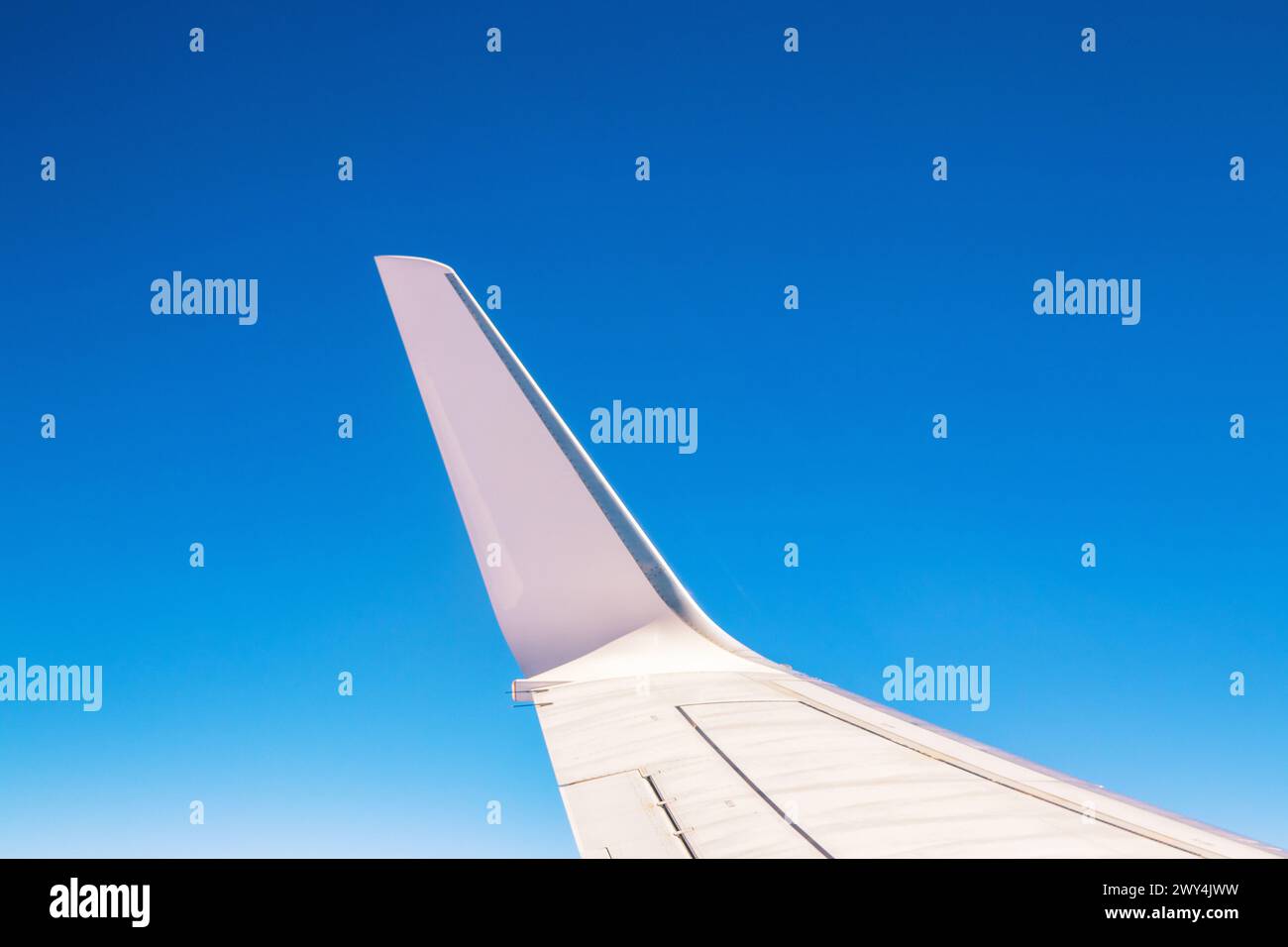 Blick auf den Teil eines Flügels des Flugzeugs oder des Flugzeugs während des Fluges aus dem Fenster mit blauem Himmel und ohne Wolken.Flügel des Flugzeugs. Stockfoto