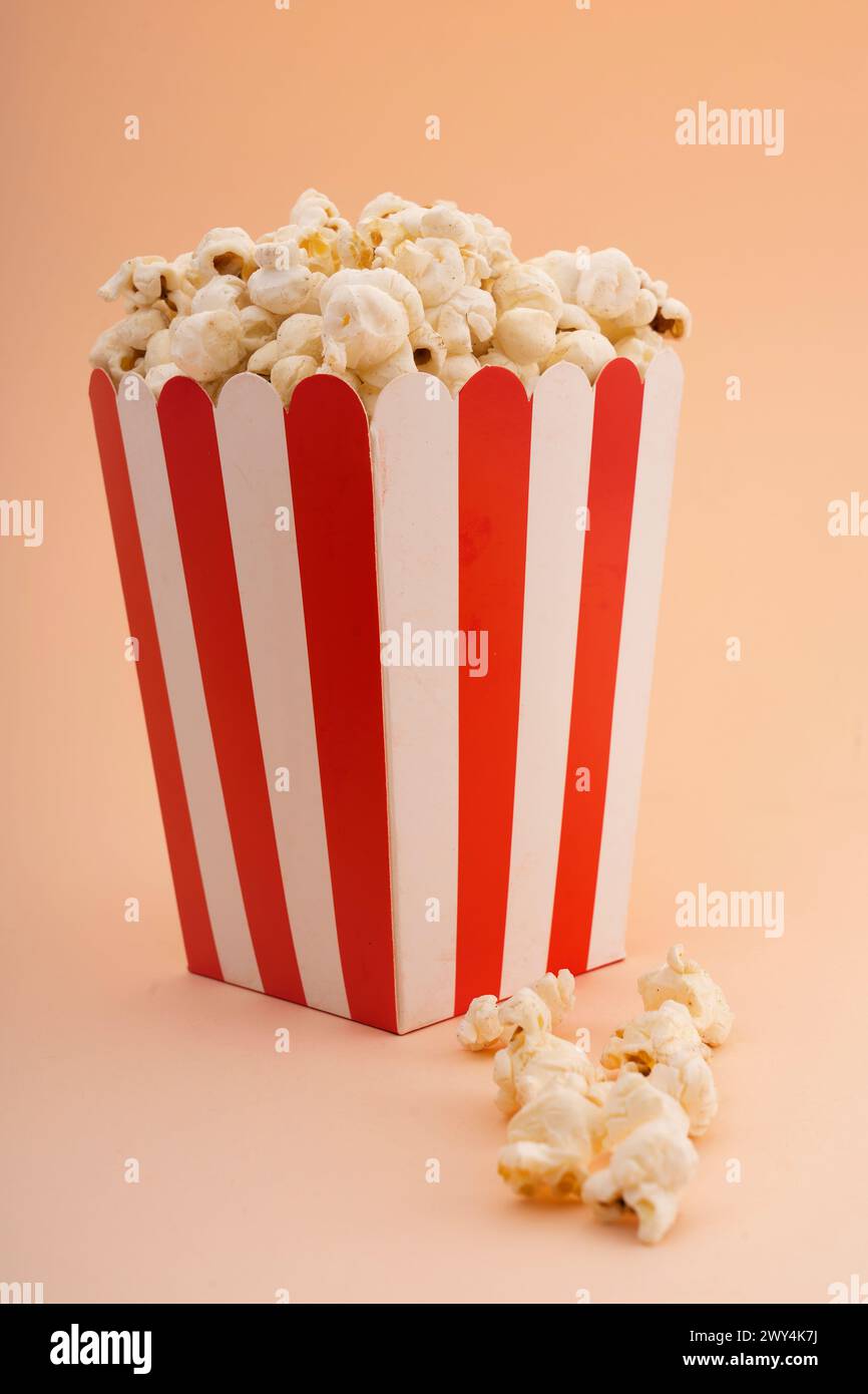 Ein gestreifter Popcorn-Eimer auf einem braunen Hintergrund. Stockfoto