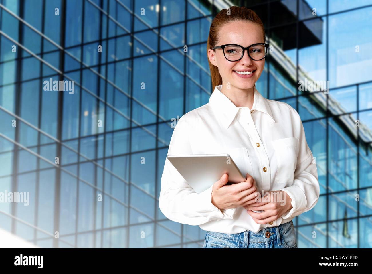 Junge Brünette Geschäftsfrau in Brille, die vor dem Geschäftszentrum oder Bürogebäude steht. Stockfoto