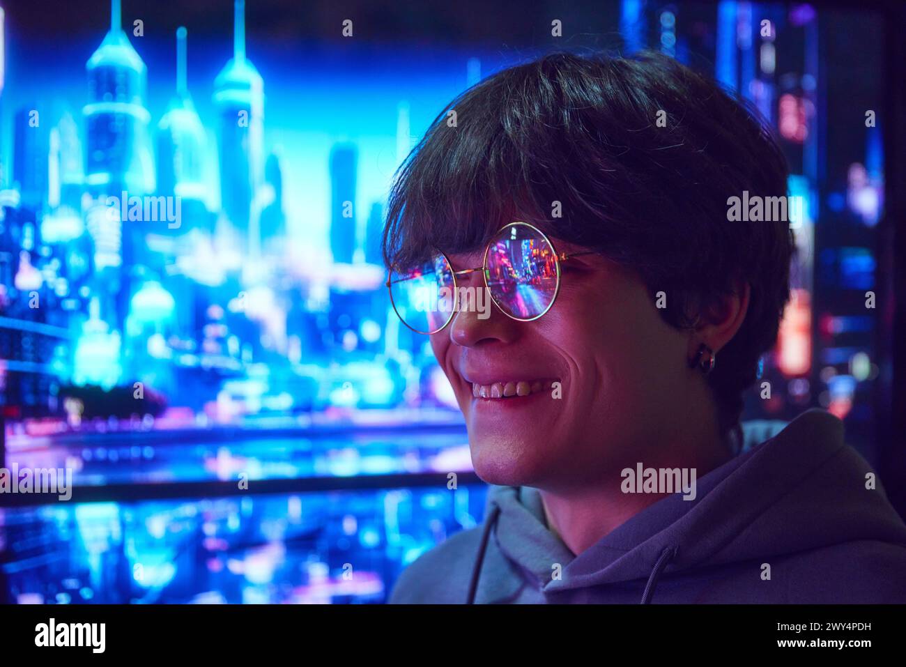 Junger Mann, der in einer Brille steht, mit einer urbanen Szene, die sich in einer Brille spiegelt. Nachtstadt mit Lichtern, Wolkenkratzern und lebhaften Straßen Stockfoto