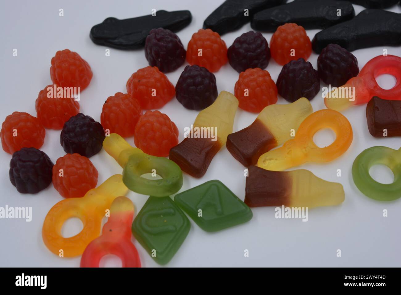 Süßigkeiten in Form eines schwarzen Autos, Himbeeren, Brombeeren, Cola-Flaschen, farbige Schlüssel, Diamanten mit dem Alphabet. Stockfoto