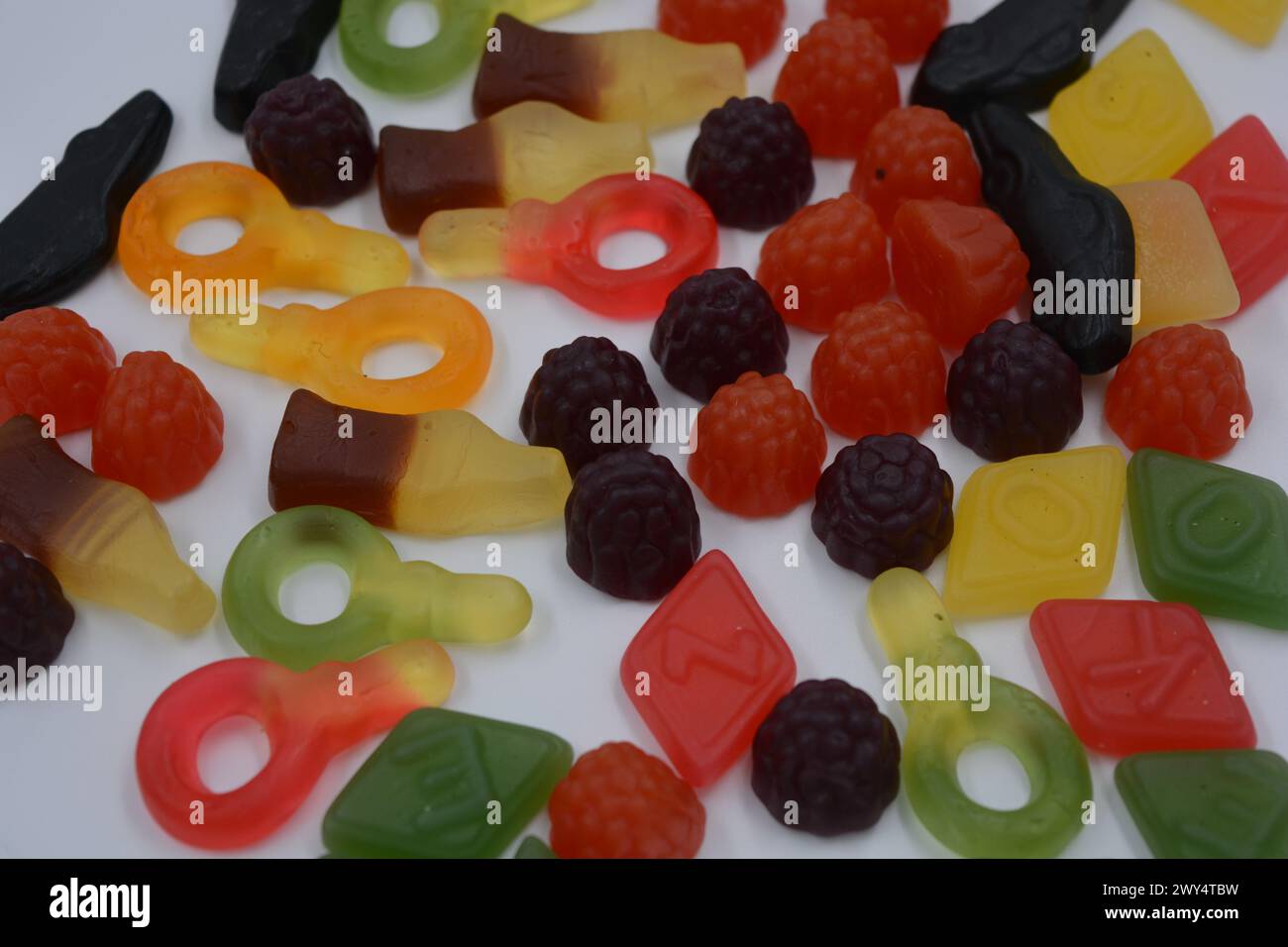 Süßigkeiten in Form eines schwarzen Autos, Himbeeren, Brombeeren, Cola-Flaschen, farbige Schlüssel, Diamanten mit dem Alphabet. Stockfoto