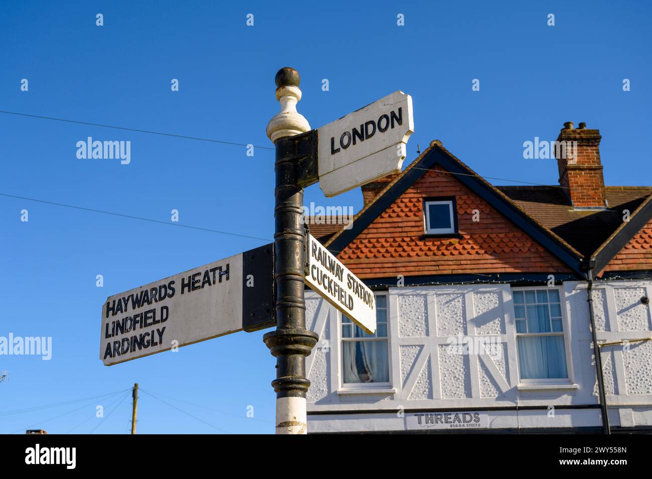 Wegweiser im alten Stil im Dorf Balcombe mit Wegbeschreibungen zu verschiedenen Städten. West Sussex, England. Stockfoto