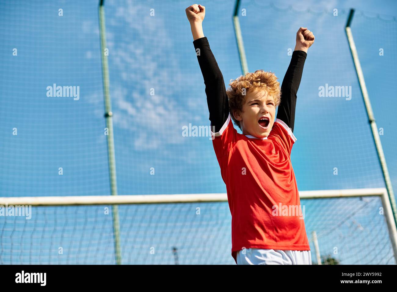 Ein kleiner Junge steht selbstbewusst auf dem Tennisplatz und hält einen Tennisschläger in der Hand. Sein konzentrierter Blick deutet auf seine Entschlossenheit und Leidenschaft hin Stockfoto