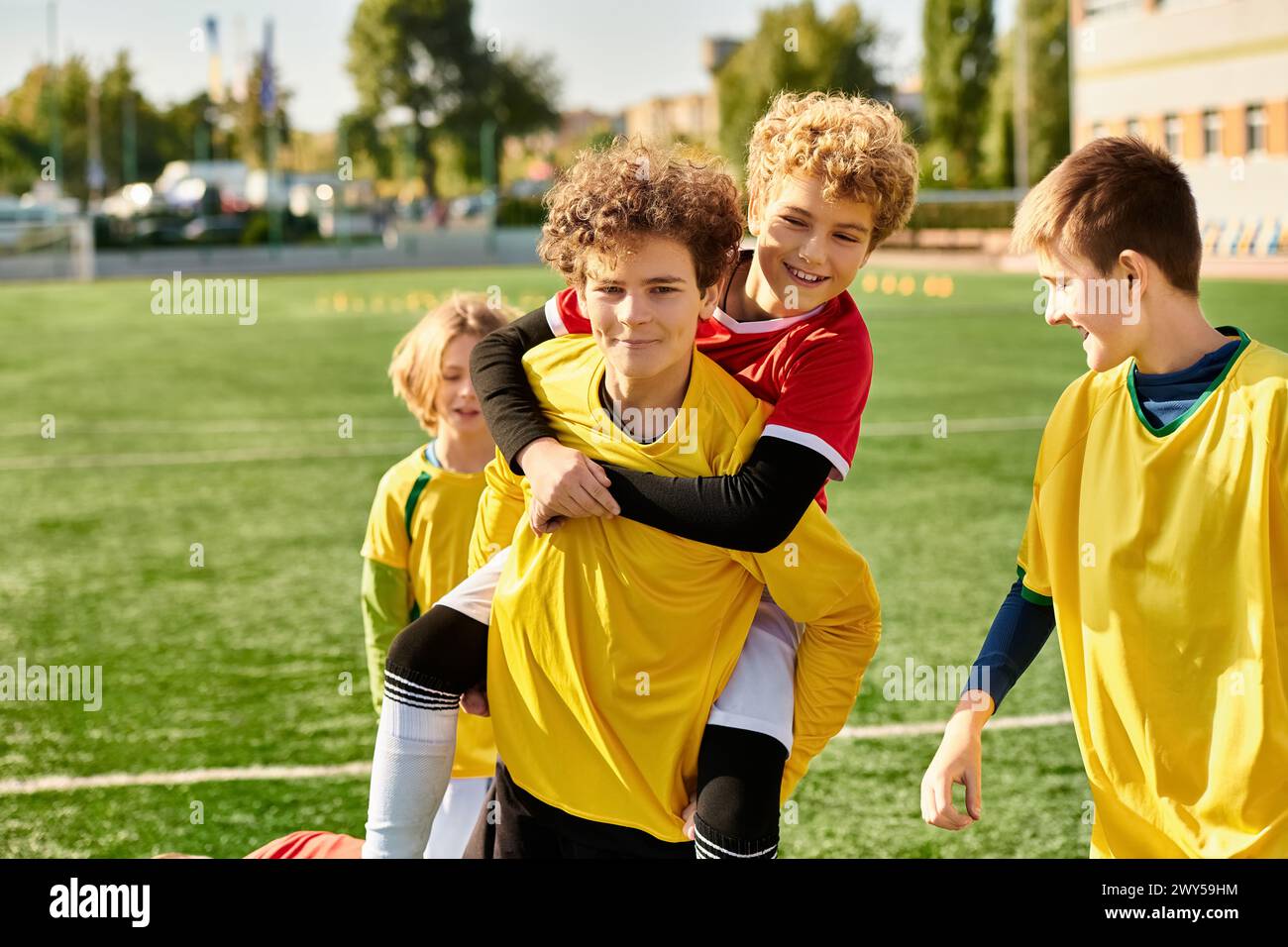 Eine Gruppe kleiner Jungen steht triumphierend auf einem Fußballfeld und feiert ihren Sieg mit Lächeln und High Fives nach einem Wettkampf. Stockfoto