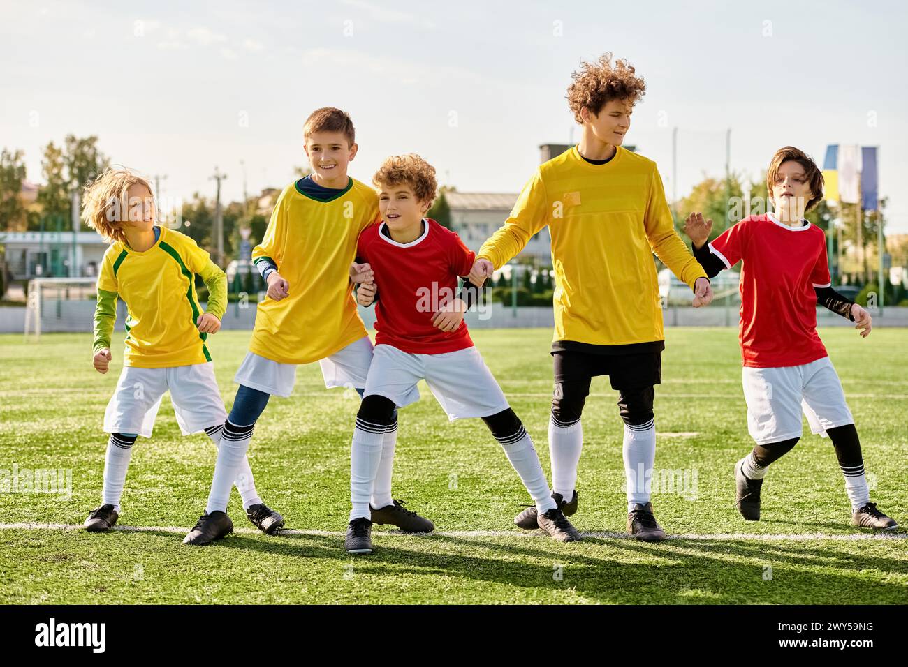 Eine Gruppe von Jungen steht stolz auf einem Fußballfeld und zeigt Einheit und Entschlossenheit. Sie werden in den warmen Glanz der untergehenden Sonne getaucht, mit Stockfoto